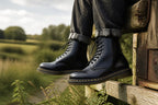 Close-up side profile of black leather boots with yellow stitched sole worn with cuffed denim outdoors